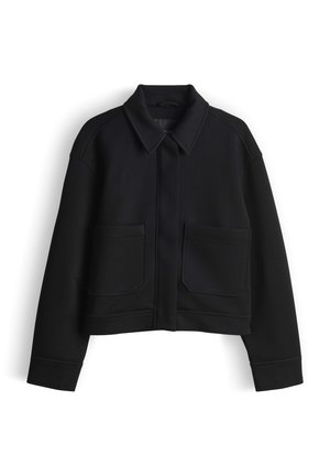 Black cropped jacket features a collared neck, two front pockets, and a smooth texture with structured shoulders. Designed with minimal detailing.