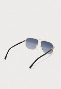 Auksiniai rėmeliai saulės akiniai su juodomis kojelėmis ir mėlynais gradientiniais objektyvais, rodomi iš viršaus ant baltos fono.