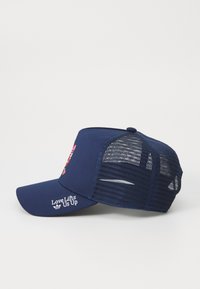 Baseball azul marinho com parte traseira em rede, aba curva e texto bordado "O Amor Nos Eleva" na frente. O contraste de cores melhora a visibilidade.