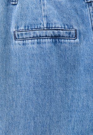 Vaaleansininen farkkukangas, jossa on sileä rakenne. Varustettu yhdellä takataskulla, jossa on ommelkorostuksia ja hienovaraista kulumaa.