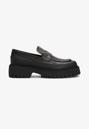 Black leather loafers with a chunky, ridged rubber sole. Features a smooth upper, rounded toe, and a simple strap across the vamp.