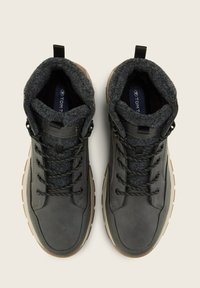 Botas de tobillo de cuero gris con un cuello forrado de lana, cordones negros y una suela de goma marrón. Presenta ojales de metal y un logo en la plantilla.
