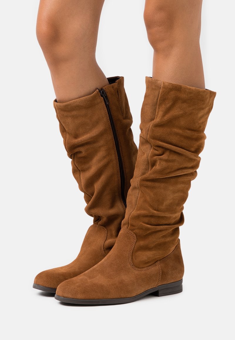 Bottes montantes en daim marron à la silhouette décontractée, dotées d'une fermeture éclair latérale et d'une semelle plate. Texture lisse avec des bouts arrondis.