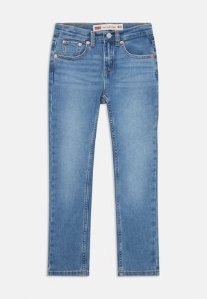 Jeans slim taper feitos de denim azul claro, com cinco bolsos, acessórios de cobre e costura amarela ao longo das costuras.