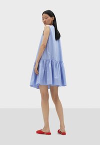 Light blue striped sleeveless dress with a flared hem. Made from lightweight fabric, featuring a gathered tier at the bottom.