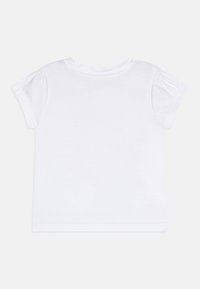 Tricou alb din bumbac, cu mâneci scurte și bombate, decolteu rotund și o textură netedă, proiectat cu un spate simplu, simplu.