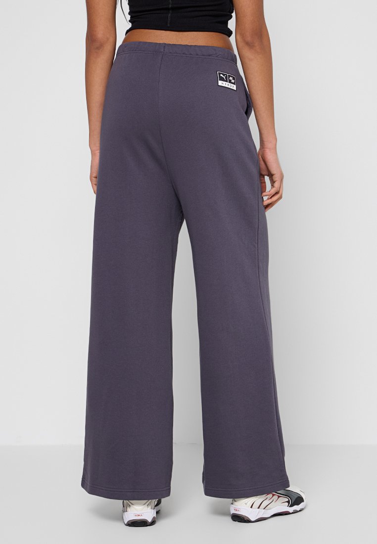 Weite, lila Sweatpants aus weichem Material, mit einem elastischen Bund und einem kleinen Logo-Patch über der rechten Tasche.