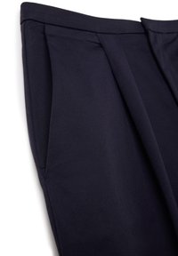 Pantalones ajustados azul marino con una textura suave, que presentan pliegues marcados y una cintura estructurada para un diseño pulido.