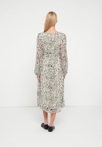 Langärmeliges, leichtes Kleid mit einem abstrakten Muster in Schwarz und Weiß. Verfügt über eine geraffte Taille und ein Schlüsselloch-Detail am Rücken.