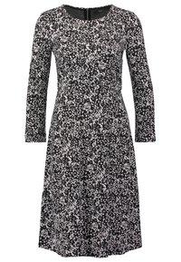 Robe longueur genou à motif floral noir et blanc avec manches longues et encolure ronde, fermeture éclair au dos.