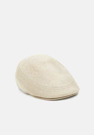 Beige gebreide muts met een gladde, ronde vorm en subtiel textuurpatroon. Lichtgewicht en ademend materiaal met een aansluitende pasvorm.