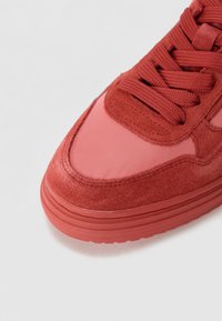 Sneaker rossa con un mix di materiali scamosciati e sintetici, punta rotonda, lacci testurizzati e suola in gomma con battistrada pronunciato.