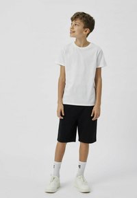 Hvid bomulds T-shirt, sorte shorts, hvide sneakers med strukturerede såler og hvide sokker. Enkel design, afslappet pasform og korte ærmer.