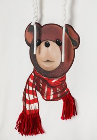 Biela mikina s kapucňou s motívom medvedej tváre a ozdobnými pletenými šnúrkami. Medveď má na sebe červeno-bielu károvanú šatku s strapcami.