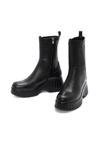 Bottines en cuir noir avec une fermeture éclair sur le côté, semelle épaisse et texturée, et une plateforme légèrement surélevée pour plus de hauteur.