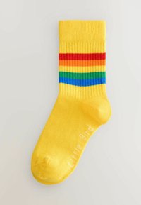 Calcetines de tobillo amarillos con textura acanalada, con rayas horizontales en rojo, naranja, verde y azul. "Pajarito" impreso en texto blanco.