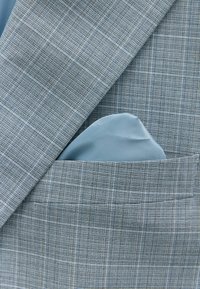 Helles blau gemustertes Sakko aus strukturiertem Stoff. Ein glattes, hellblaues Einstecktuch ist sauber in der Brusttasche platziert.