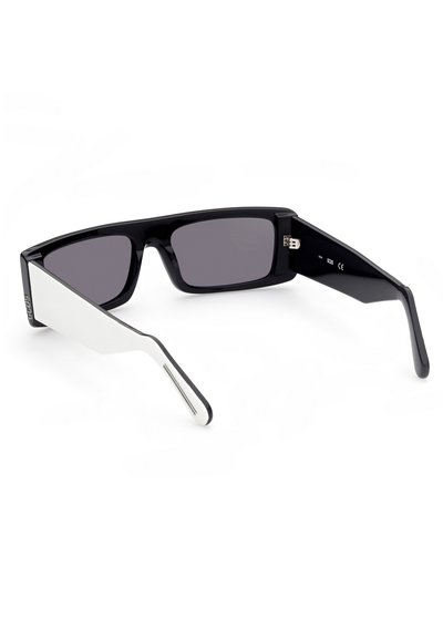 Occhiali da sole neri con lenti scure. Un braccio presenta un accento bianco con un design curvo. Texture liscia e forma geometrica moderna.