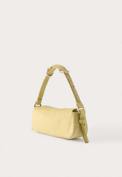 Malá žltá kabelka s nastaviteľným popruhom a striebornou prackou na jednoduchom svetlom pozadí.