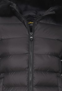 Giubbotto trapuntato nero con chiusura a zip frontale e un accento in pelliccia sintetica sul cappuccio. Tessuto morbido e imbottito per il calore.