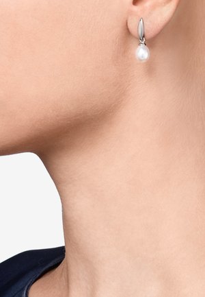 Ohrringe in Silberfarbe zeichnen sich durch einen perlenähnlichen Tropfen und ein elegantes, geschwungenes Design aus. Die Rückseite hat ein poliertes Finish, was die Eleganz unterstreicht.