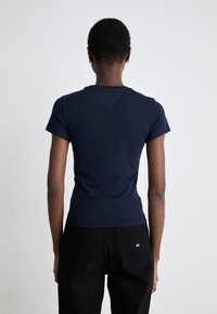 Maglietta fitted blu navy con maniche corte, realizzata in cotone. Colore uniforme, design semplice e scollo rotondo. Indossata con pantaloni neri.