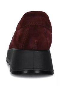 Sneaker rossa in suede con suola in gomma nera, forma arrotondata, dettagli cuciti e tacco basso. La vista posteriore mette in evidenza la morbidezza della texture e il design.