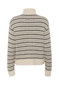 Krämfärgad stickad tröja med svart geometriskt mönster, hög krage, ribbade manschetter och nederkant, med en boxig silhuett och mjuk textur.