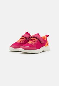 Helle rosa und orange Kinder-Sportschuhe mit weißen Sohlen, Netzeinsätzen, Klettverschluss und Schnürung, schräg auf weißem Hintergrund.