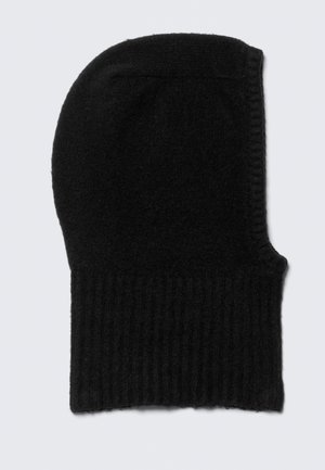 Bonnet noir en tricot avec une texture côtelée, légèrement allongé sur le dessus, fabriqué à partir d'un matériau doux ; présente un design sans couture.