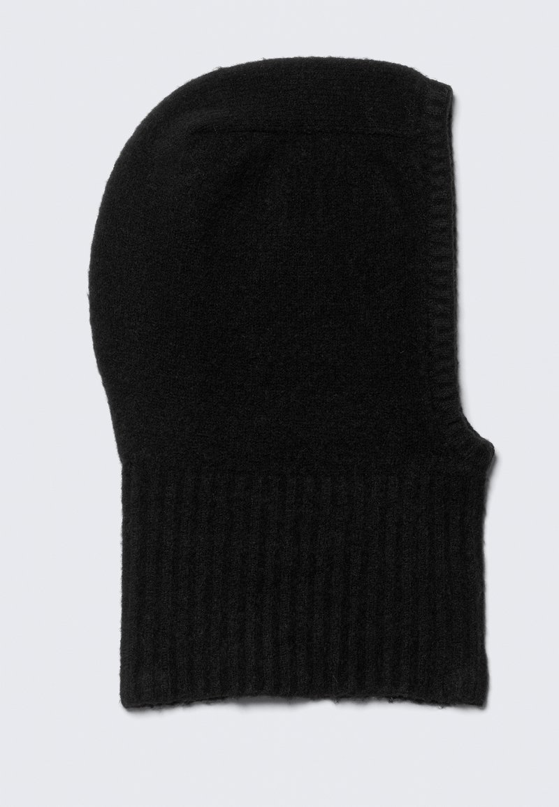 Gorro de malha preto com textura canelada, ligeiramente alongado na parte superior, feito de material macio; apresenta um design sem emendas.