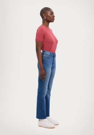 Red short-sleeve fitted knit top paired with light blue high-waisted jeans, featuring a straight leg and subtle fading. White sneakers complete the look.