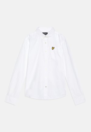 Biała, długorękawowa koszula na guziki z kołnierzem w kształcie mankietu oraz żółtym logo ptaka wyszywanym na lewej piersi.