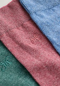 Három kötött zokni zöld, rózsaszín és kék színekben. Mindegyiken finom virágmintás hímzés látható. Texturált anyag bordázott mandzsettákkal.