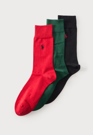 Tres calcetines tipo 'crew' doblados en colores rojo, verde y negro, cada uno con un pequeño logo bordado cerca del puño superior.