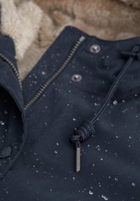 Marine waterproof jack featuring a gestructureerd oppervlak met waterdruppels, een metalen rits en een capuchontouw dat is vastgebonden met een gevlochten koord.