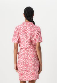 Abito a maniche corte con motivo geometrico rosa e bianco. Presenta un colletto, una cintura in vita, una lunghezza fino al ginocchio e un tessuto testurizzato.