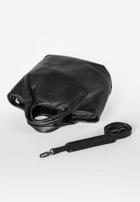 Zwarte leren tas met een gestructureerde afwerking, een ruime opening en een afneembare leren schouderband. Het ontwerp heeft een afgeronde bovenkant en subtiele branding.