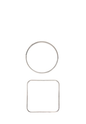 Un anneau en métal argenté circulaire au-dessus d'un anneau en métal argenté carré aux coins arrondis sur un fond blanc.