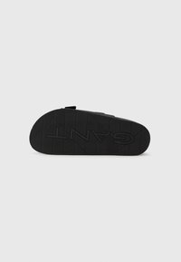 Black rubber sole with a textured grip pattern; features embossed branding and a contoured shape for comfort and traction.