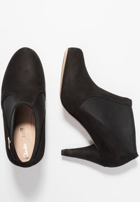 Svarta ankelboots i mocka och tyg, med stilettklack, rund tå och elastiska sidopaneler för enkel påtagning.