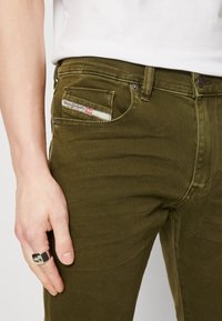 Olivgröna denimjeans har en klassisk femficksdesign med en liten märkesetikett på framfickan och subtila sömdetaljer.