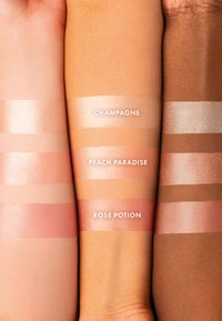 Tre tonalità di pelle con campioni di illuminante: Champagne (chiaro, luminoso), Peach Paradise (pesca, finitura satinata), Rose Potion (rosa, luminoso).