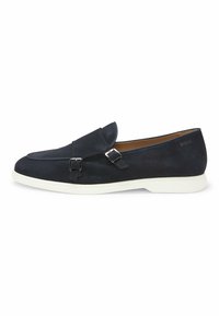 Navy suede loafers with decorative buckles, white rubber sole, rounded shape, and a streamlined design. Minimal branding on the heel.