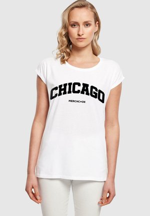 Witte katoenen t-shirt met opgerolde korte mouwen, met een zwarte "CHICAGO" graphic en "MERCHCODE" eronder in vette letters. Gladde textuur.