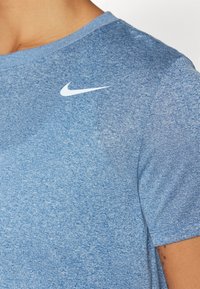 Blå atletisk T-shirt i mjukt material, med rund halsringning och korta ärmar. Vit Nike-logotyp på övre vänstra bröstet.
