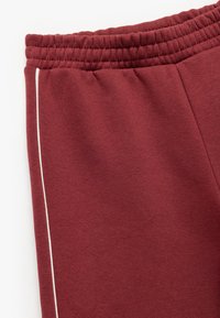 Bordeaux sweatpants med elastisk talje og sidelister i en kontrastfarve. Blød tekstur med et afslappet fit-design.