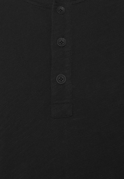 Black henley shirt with four black buttons. Material appears soft and textured. Features a simple collar and small button placket.