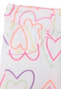 Indumento bianco con motivi a cuore multicolori in ricami rosa, arancione, verde e viola; presenta una vita e una piccola tasca.