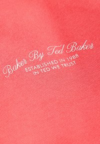 Korallroosa kangas, millel on valge kiri "Baker By Ted Baker" ning allpool "ESTABLISHED IN 1988" ja "IN TED WE TRUST".